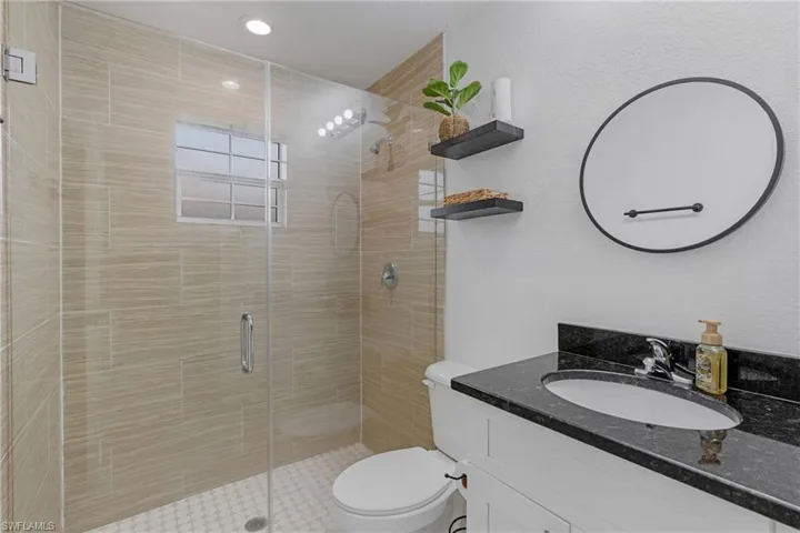 Bathroom with an enclosed shower, large vanity, and toilet