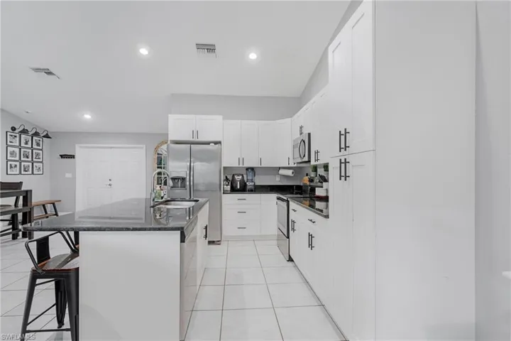 Kitchen with stainless steel appliances, a kitchen island with sink, a breakfast bar area, sink, and light tile floors