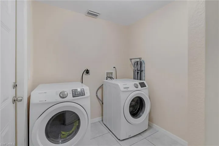 Clothes washing area with hookup for an electric dryer, washing machine and clothes dryer, washer hookup, and light tile flooring