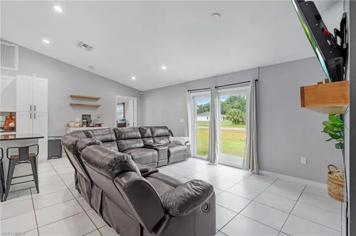 Living room featuring lofted ceiling and light tile floors