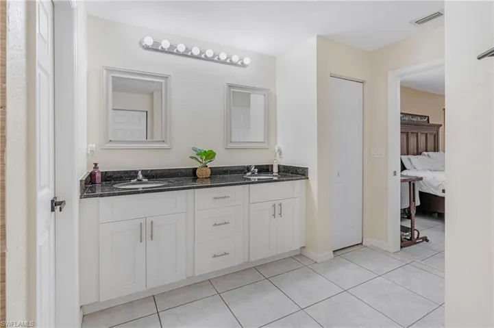 Bathroom featuring vanity with extensive cabinet space, dual sinks, and tile floors