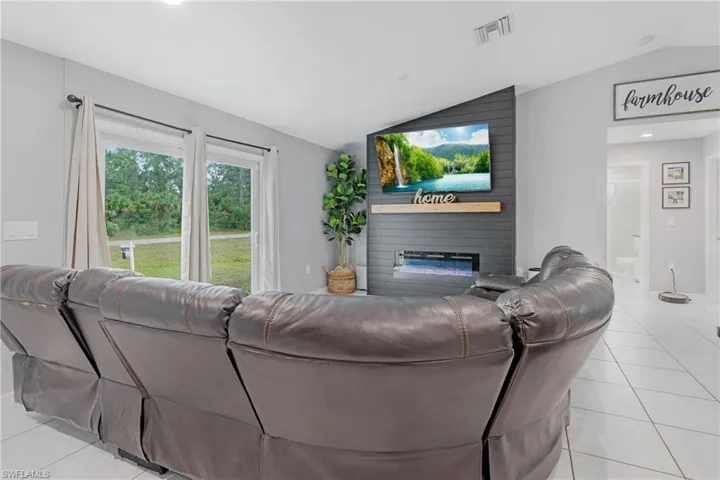 Tiled living room with a fireplace and lofted ceiling