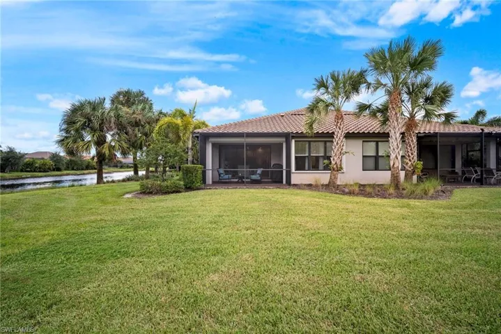 Back of property with a water view, a sunroom, and a lawn