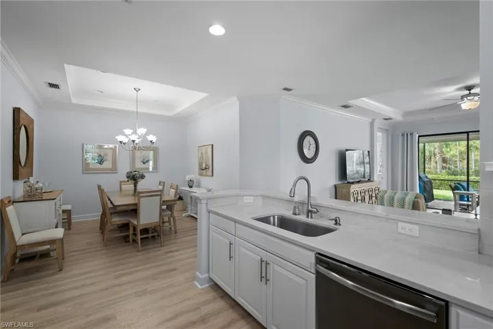 Kitchen featuring dishwasher, light hardwood / wood-style flooring, sink, decorative light fixtures, and white cabinets