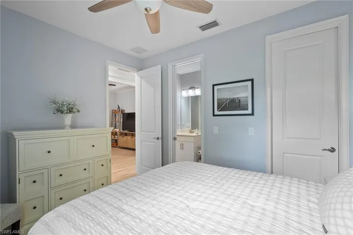 Bedroom with light hardwood / wood-style flooring, ceiling fan, ensuite bathroom, and sink