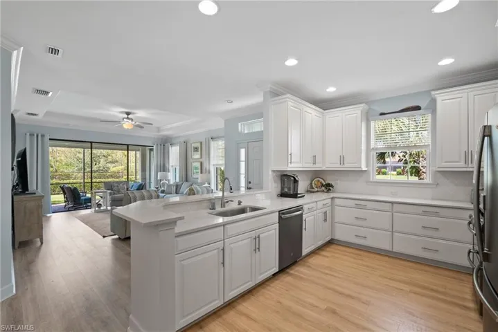 Kitchen with appliances with stainless steel finishes, kitchen peninsula, white cabinetry, and plenty of natural light