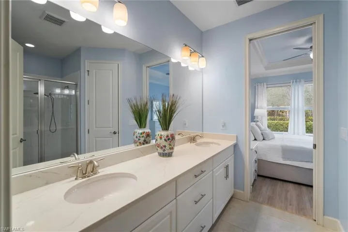 Bathroom with a shower with shower door, ceiling fan, tile patterned floors, vanity, and ornamental molding