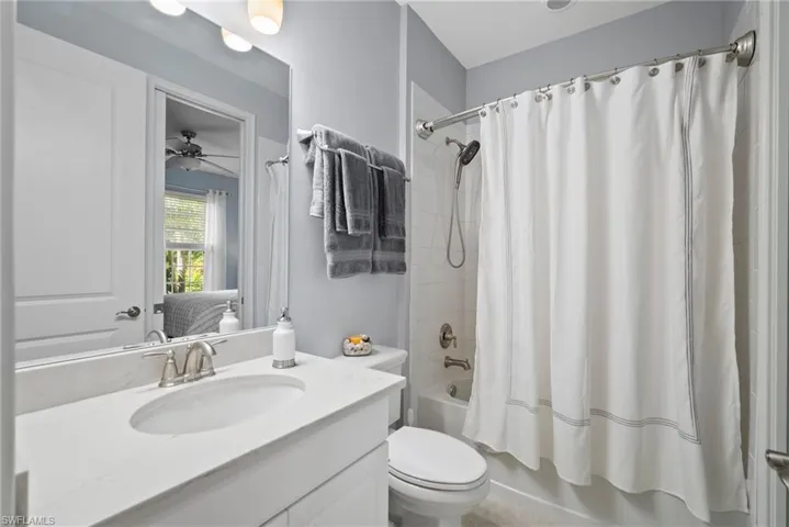 Full bathroom featuring vanity, shower / bath combination with curtain, toilet, and ceiling fan