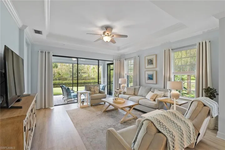 Living room with a healthy amount of sunlight, a tray ceiling, and light wood-type flooring