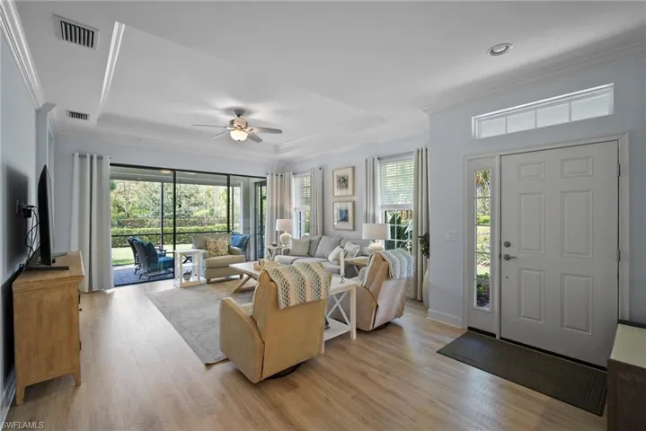 Living room with ornamental molding, ceiling fan, light wood-type flooring, and plenty of natural light