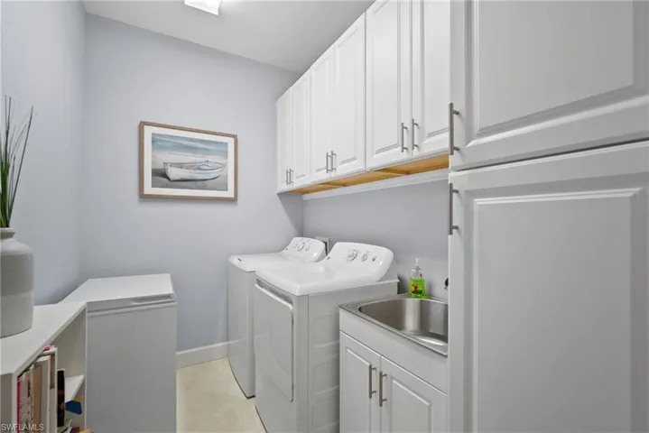 Washroom featuring cabinets, washer and dryer, and light tile patterned floors