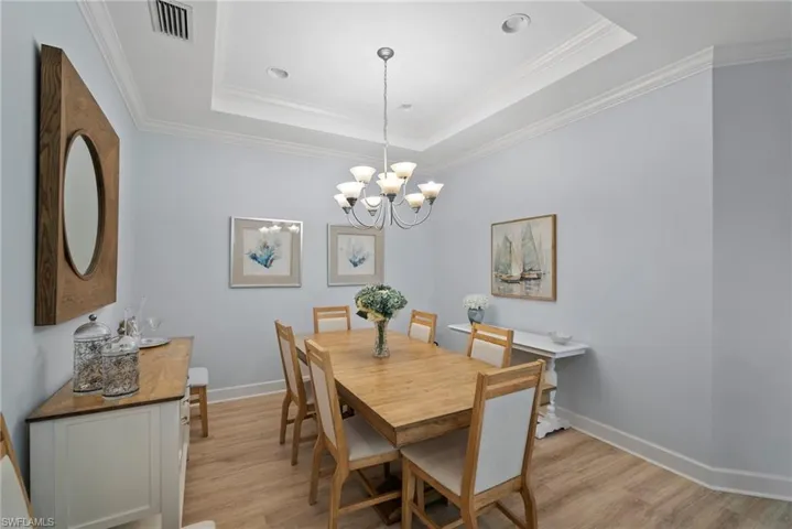 Dining room featuring a notable chandelier, crown molding, a tray ceiling, and light hardwood / wood-style flooring