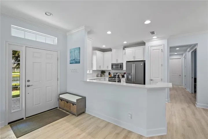 Kitchen with a wealth of natural light, appliances with stainless steel finishes, kitchen peninsula, and white cabinetry