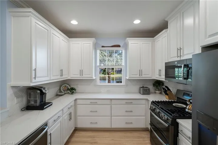 Kitchen featuring tasteful backsplash, appliances with stainless steel finishes, light hardwood / wood-style flooring, and white cabinets