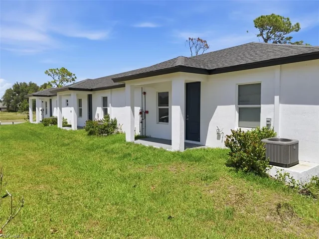 Modern exterior featuring white stucco finish, dark gray shingle roof, dark gray front doors, and white columned entryways