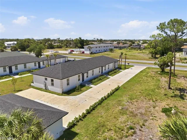 Modern residential buildings with dark shingle roofs, light-colored exteriors, and established driveways