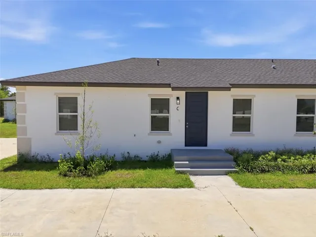 Contemporary facade featuring white stucco, dark gray pitched roof, and a contrasting dark blue entry door