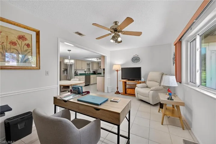 Living area featuring ceiling fan, light tile patterned floors, and a textured ceiling