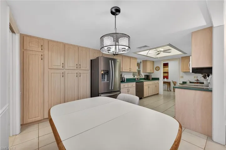 Kitchen with light brown cabinetry, light tile patterned floors, pendant lighting, and stainless steel appliances