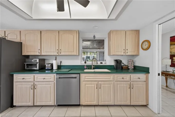 Kitchen featuring stainless steel appliances, ceiling fan, dark countertops, and light brown cabinetry