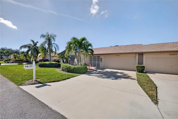 Ranch-style home with a front yard, concrete driveway, stucco siding, and an attached garage