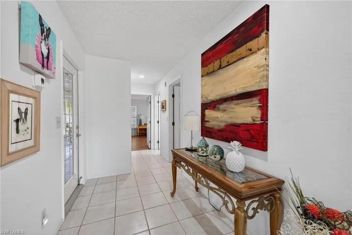 Hallway with a textured ceiling, light tile patterned flooring, and recessed lighting