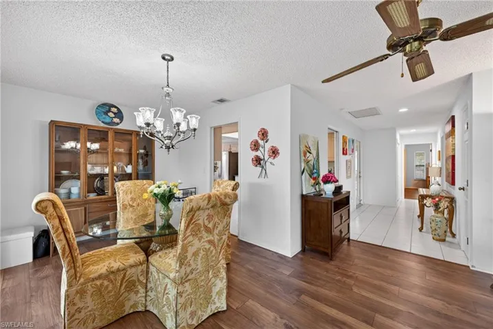 Dining area with wood finished floors, a textured ceiling, ceiling fan, and a chandelier