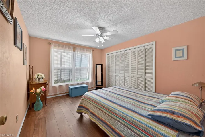 Bedroom with hardwood / wood-style floors, a textured ceiling, and a ceiling fan