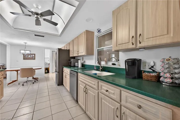 Kitchen featuring dark countertops, an office area, pendant lighting, light tile patterned floors, and stainless steel appliances