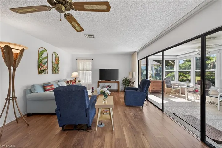 Living room featuring ceiling fan, wood finished floors, and a textured ceiling