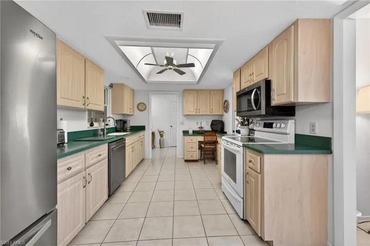 Kitchen with dark countertops, appliances with stainless steel finishes, and light brown cabinets