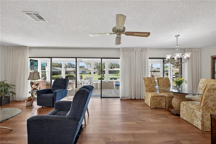Living area featuring plenty of natural light, a chandelier, hardwood / wood-style floors, a textured ceiling, and ceiling fan