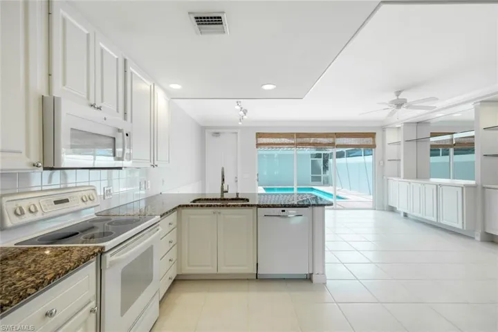 Kitchen featuring white cabinetry, granite countertops, white tile backsplash, and built-in appliances