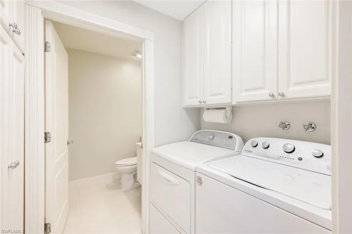 Laundry area featuring white cabinetry, a built-in paper towel holder, and tile flooring