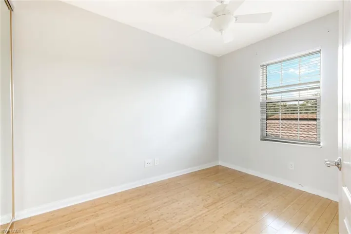 Bright room featuring wood-finish flooring, a window with blinds, and a ceiling fan