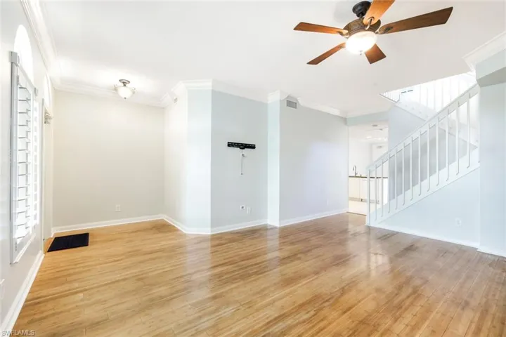 Spacious interior featuring wood-finish flooring, crown molding, and a ceiling fan