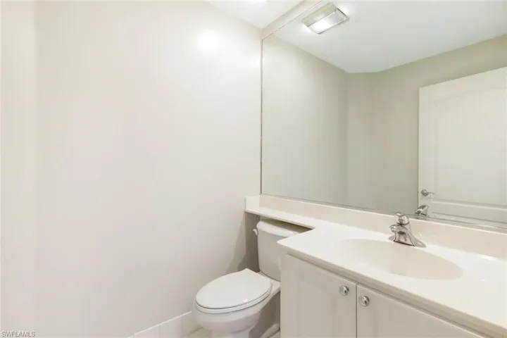 Bathroom featuring a single vanity with under-sink cabinetry, an integrated sink, a large wall-mounted mirror, and a white toilet