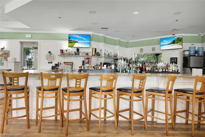 L-shaped bar with a stone-finish countertop and white paneled base