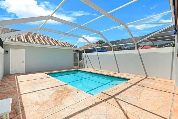 Screened outdoor swimming pool area featuring a concrete deck with irregular flagstone pattern
