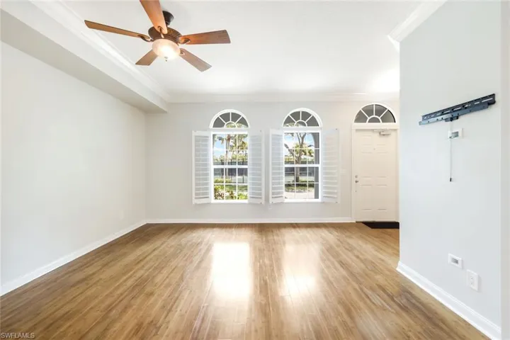 Bright interior space featuring wood-finish flooring, a ceiling fan, and crown molding