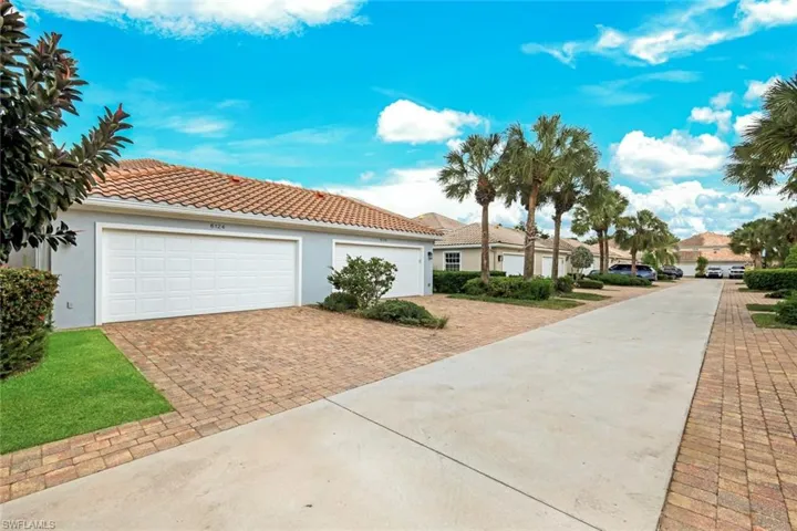 Mediterranean-style residence featuring a terracotta tile roof, light blue stucco exterior, and a two-car garage with white panel doors