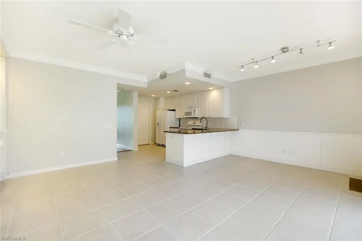 Open-concept living area featuring large format tile flooring, crown molding, and a ceiling fan