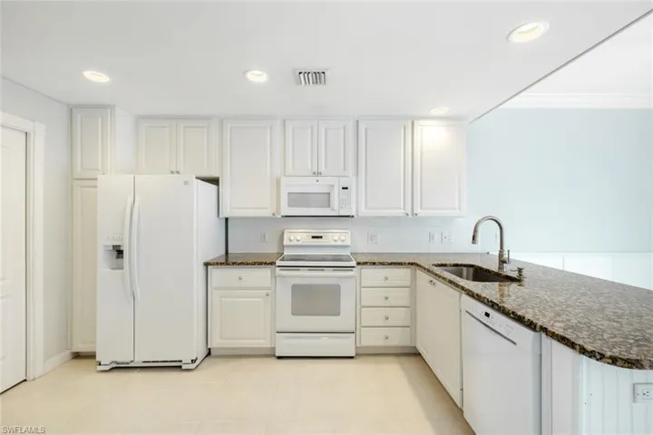 Kitchen featuring white cabinetry, granite countertops, white tile backsplash, integrated sink, and recessed lighting