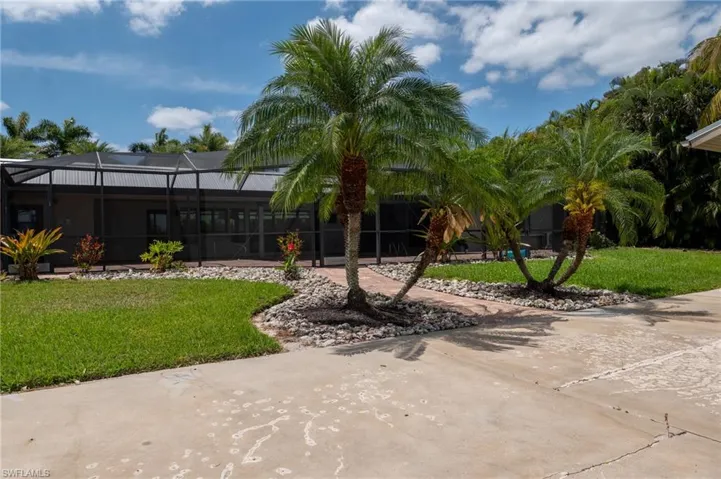 View of front facade featuring glass enclosure and a front yard