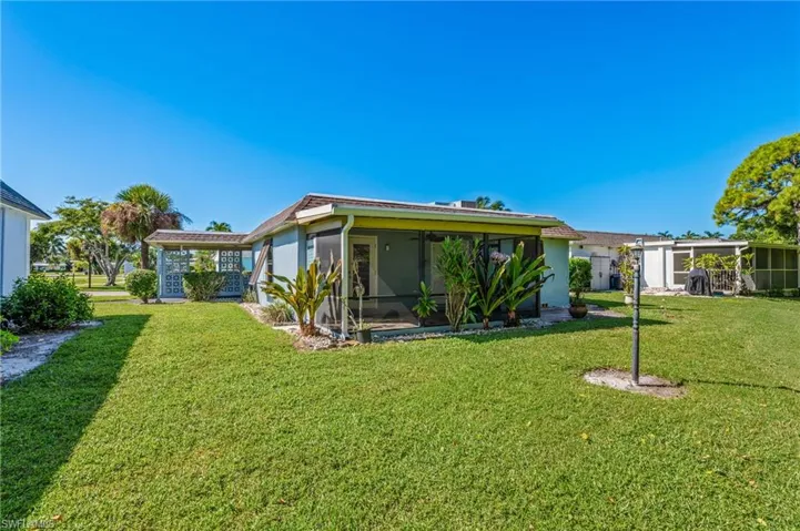 Back of property featuring a yard, a sunroom, and stucco siding