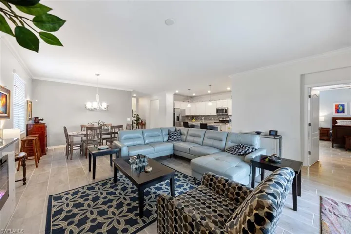 Living room featuring crown molding, suspended lighting, and wood tiled floors