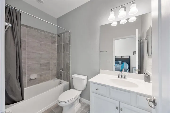 Ensuite bathroom with shower / tub combo, a textured wall, and vanity