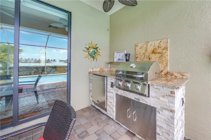 View of patio with a grill, a sunroom, ceiling fan, a water view, and glass enclosure