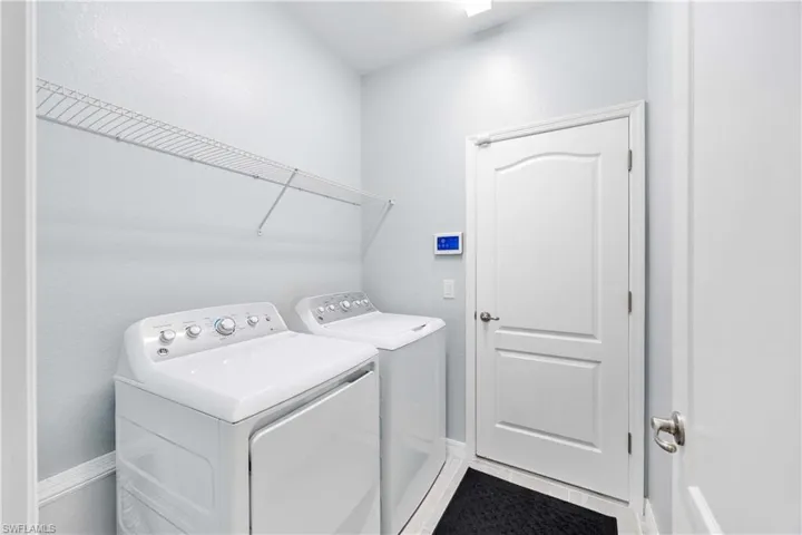 Laundry area with washer and clothes dryer and tile flooring.