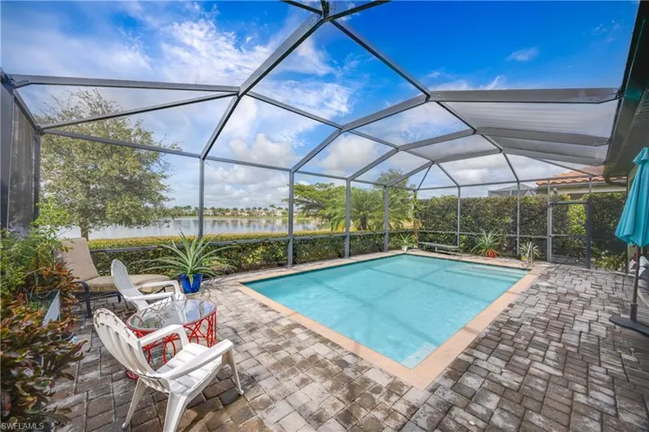 Swimming pool featuring a sunroom, a patio area, a water view, and a lanai